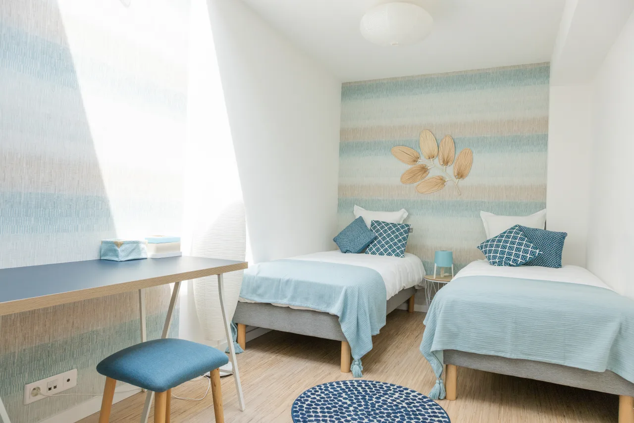 Loft La Vesée — chambre pastel avec ses deux lits simples et le petit bureau