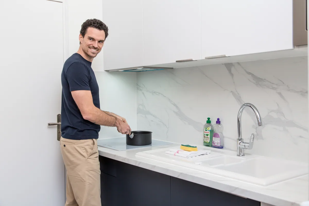 Maison La Vesée, l'appartement Alpinia, un homme cuisinant sur la plaque de cuisson