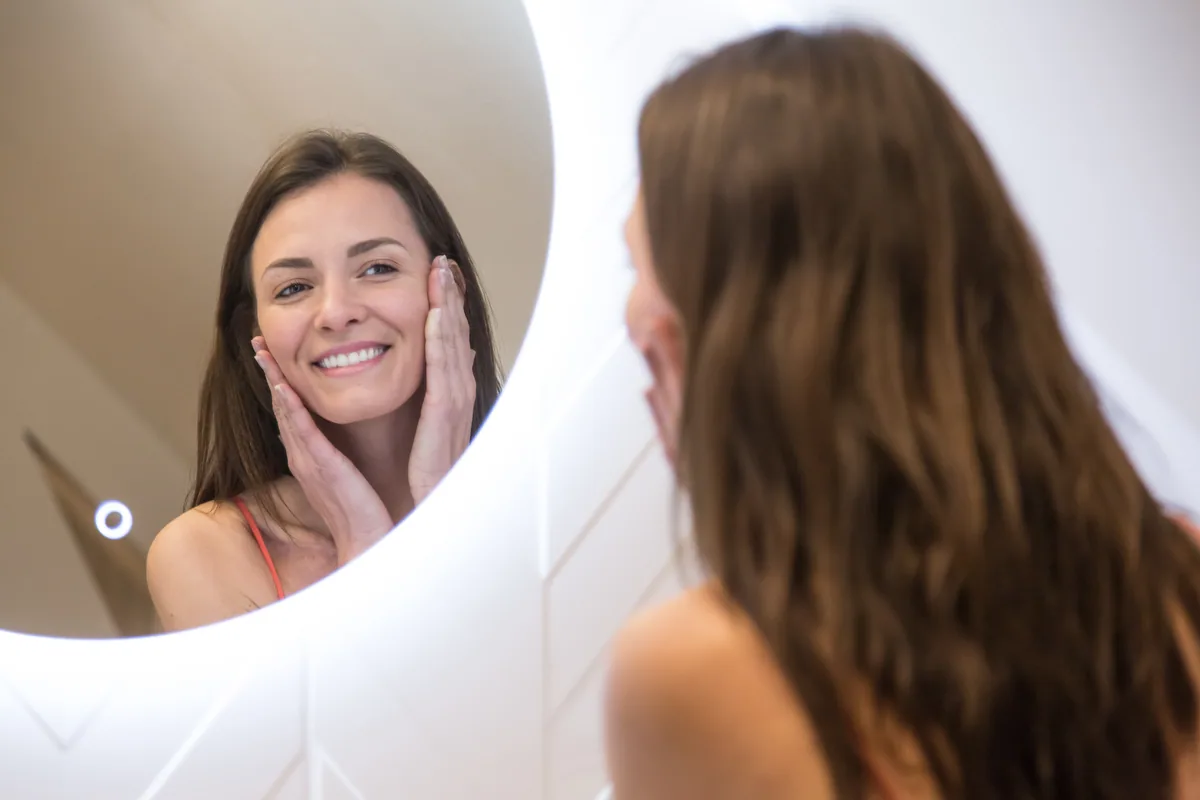 Maison La Vesée, l'appartement Alpinia, la salle de douche, une femme se mettant de la crème devant le miroir