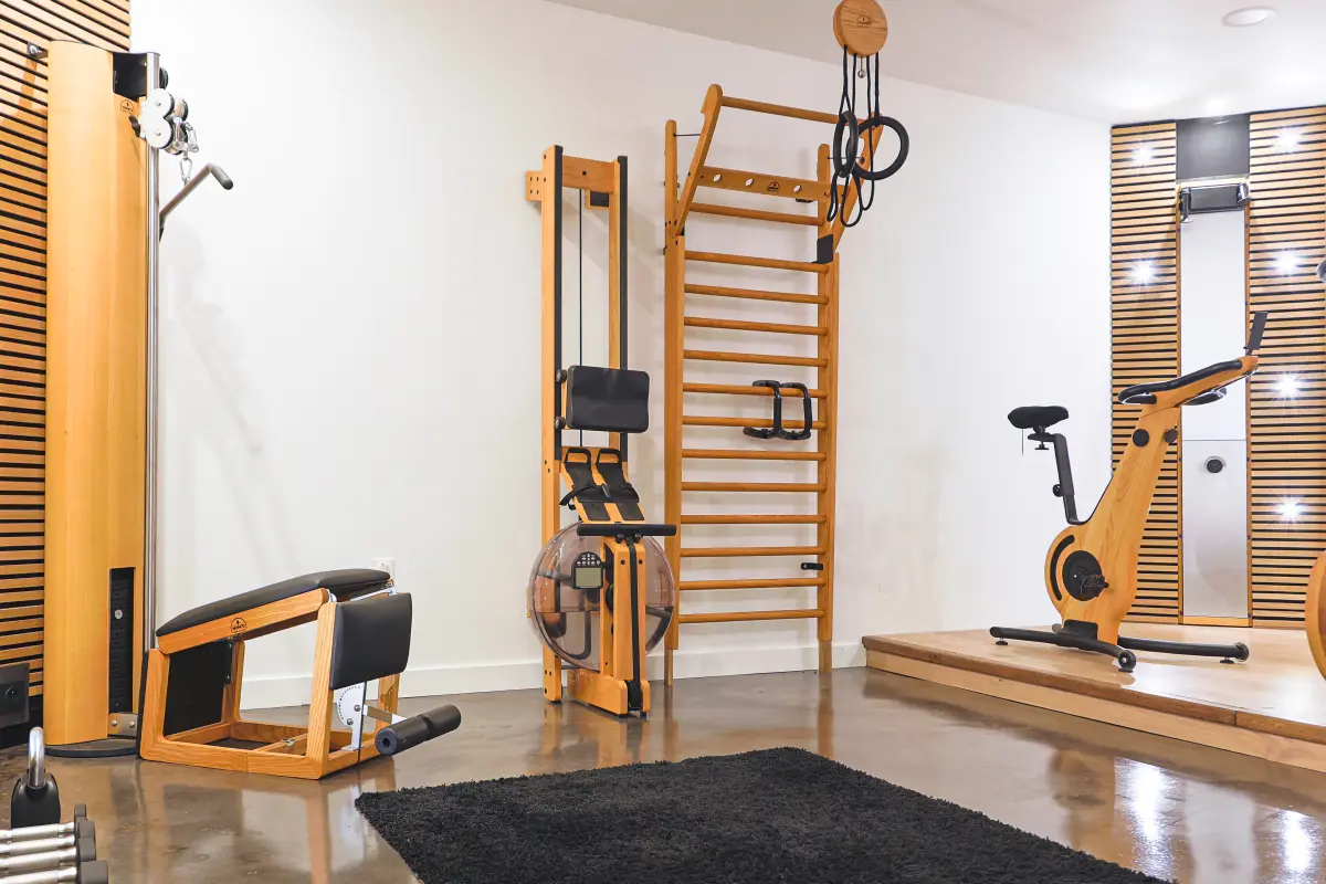 Maison La Vesée, l'Annexe, la salle de sports, l'espace musculation : espalier NOHrD, banc à abdominaux Tria Trainer, poulie SlimBeam et anneaux de traction, le vélo en arrière-plan