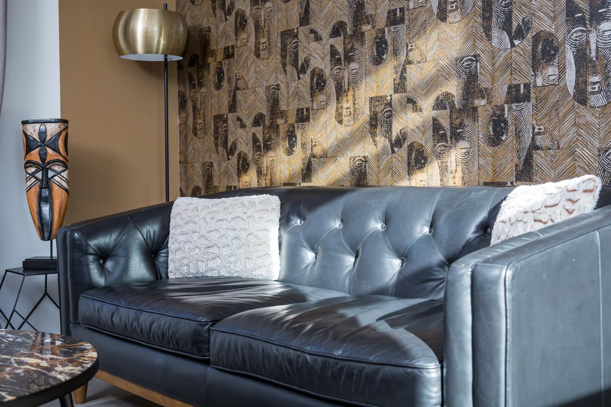 Maison La Vesée, l'appartement Heliconia, le salon, vue rapprochée sur le canapé en cuir noir et ses coussins