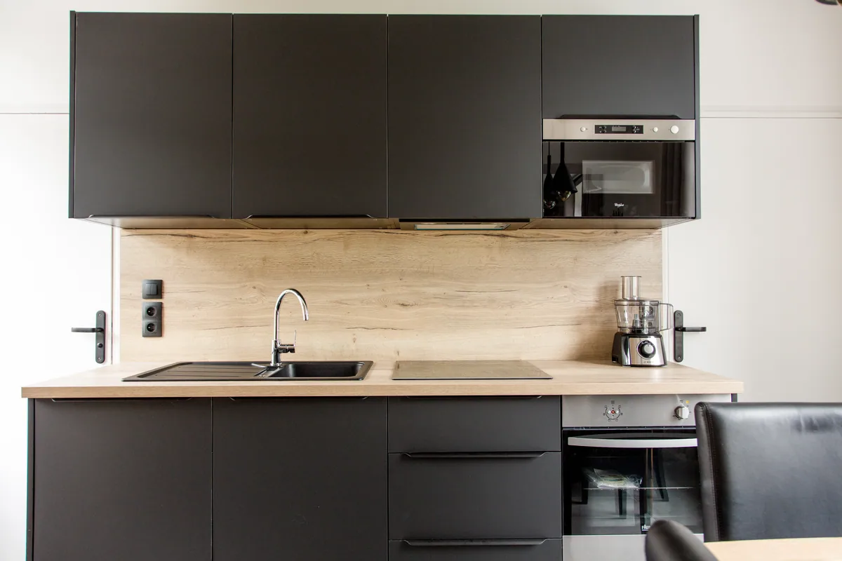 Maison La Vesée, l'appartement Heliconia, la cuisine, meubles noirs côté évier et cuisson, vue de face