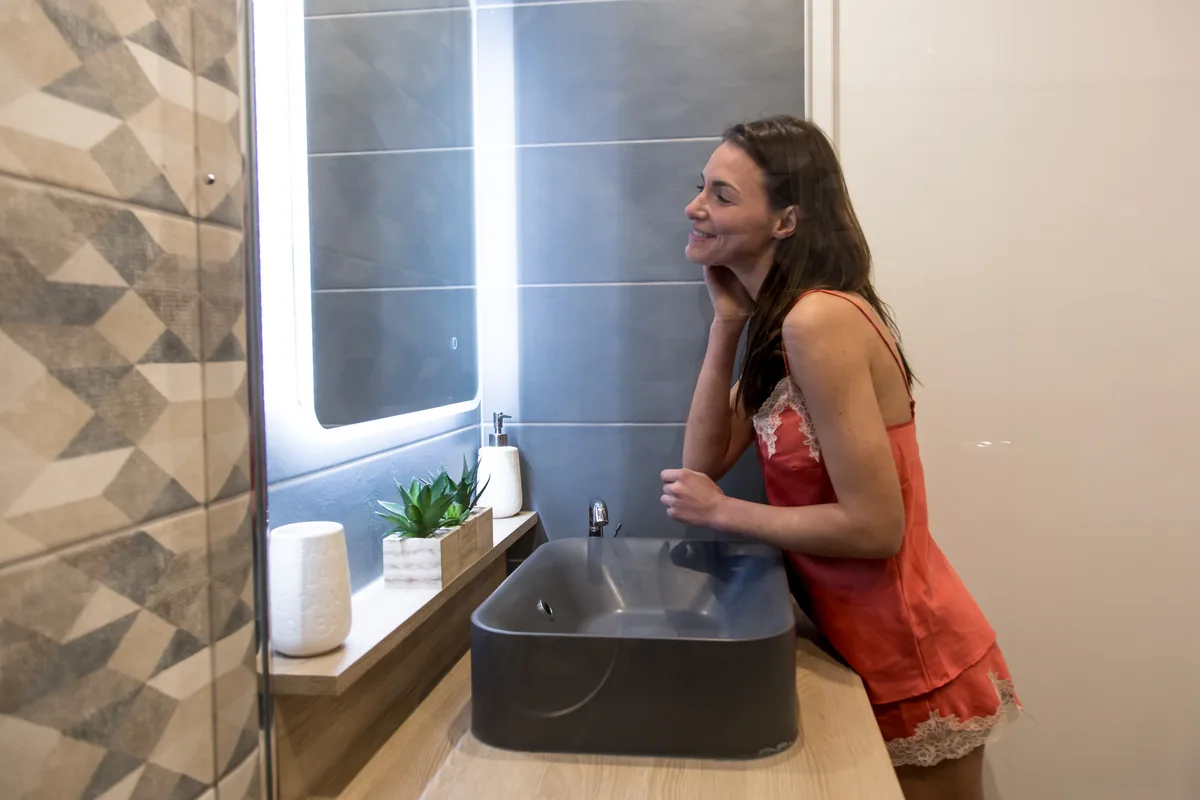 Maison La Vesée, l'appartement Nymphéa, la salle de douche, une femme se mettant de la crème devant le miroir