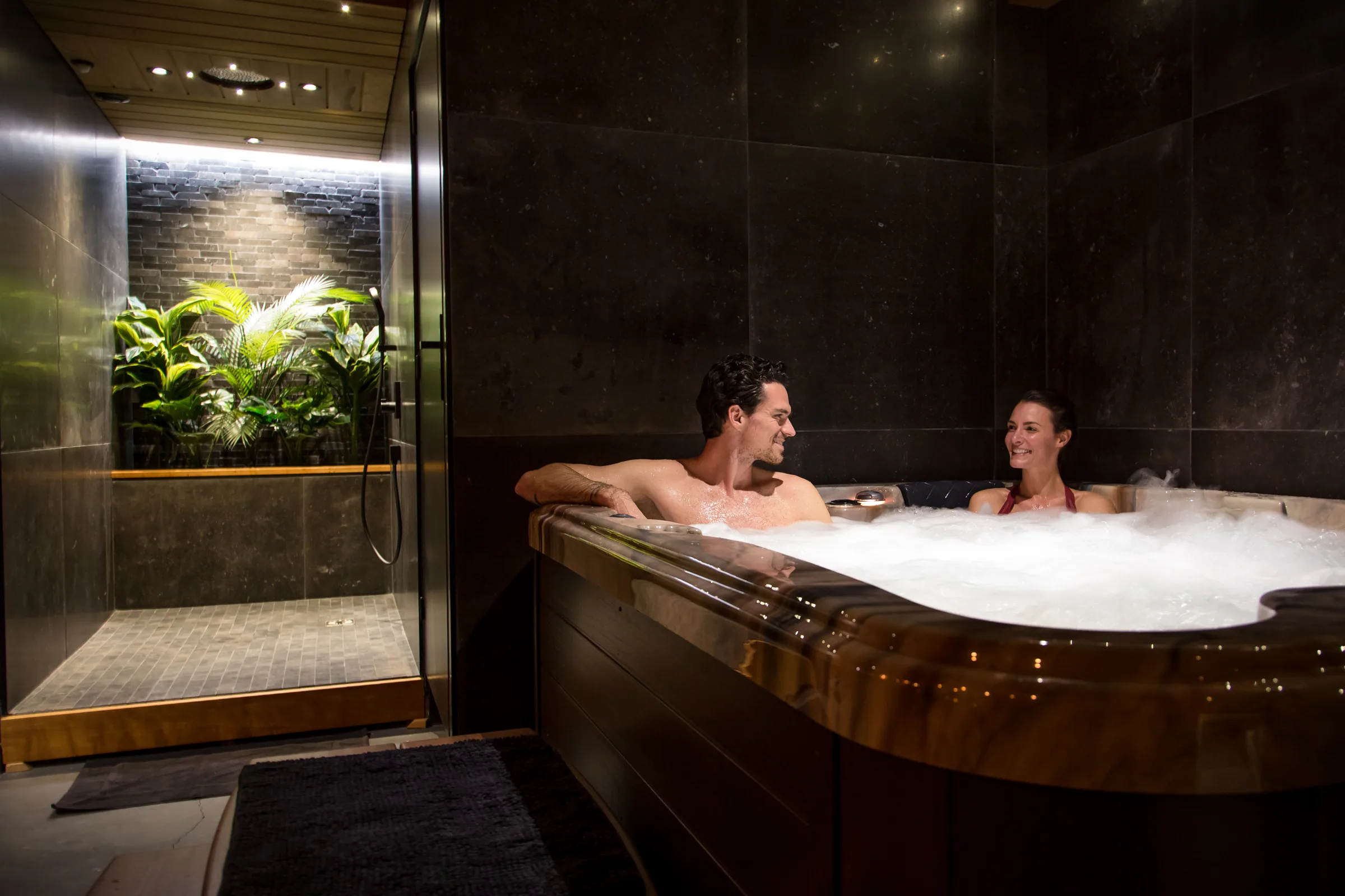 L'espace bien-être de Maison La Vesée, le bain à remous avec douche sensorielle et mur végétal en arrière-plan