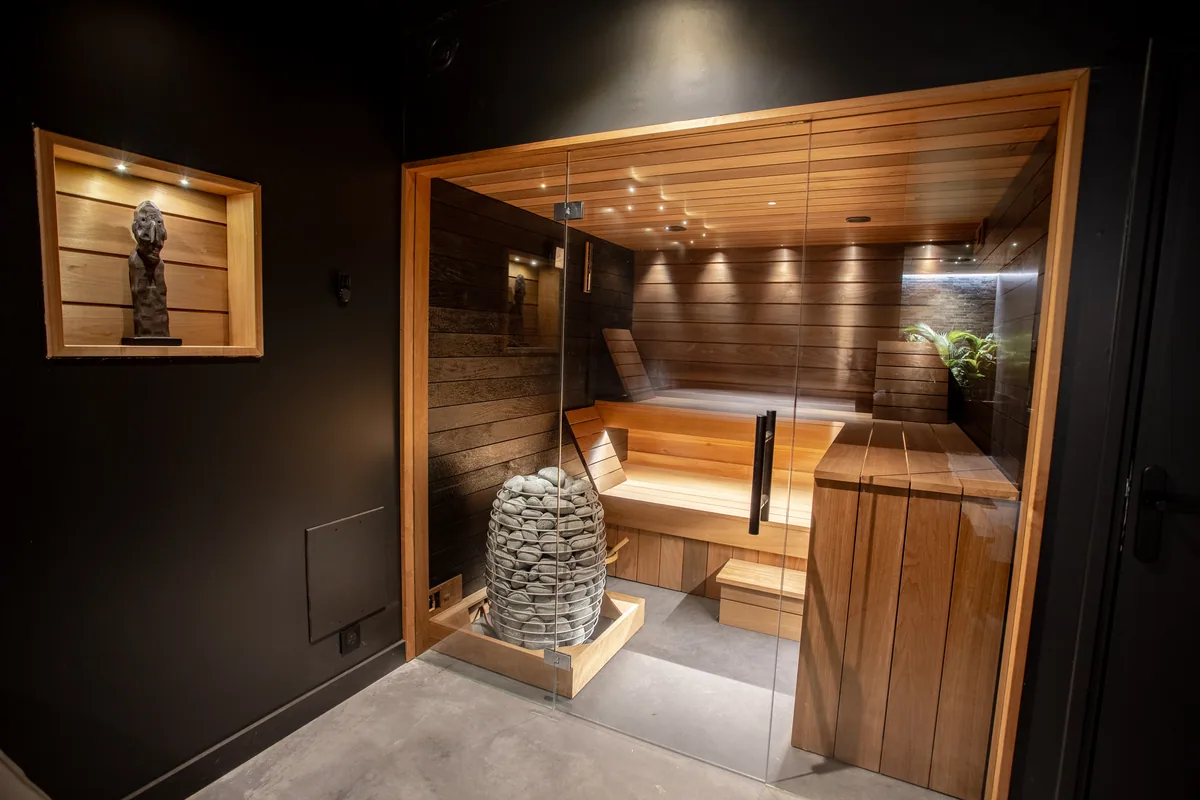 L'Espace bien-être de Maison La Vesée, vue générale sur l'intérieur du sauna, le four et les bancs en bois