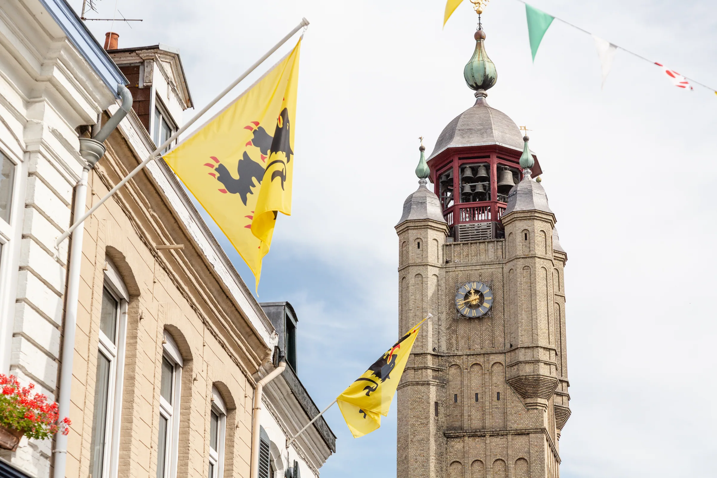 Bergues, le beffroi UNESCO et les drapeaux flamands sur la place du marché