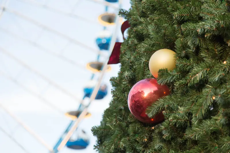 Rote und goldene Kugeln an einer Tanne, dahinter das Riesenrad, am späten Nachmittag