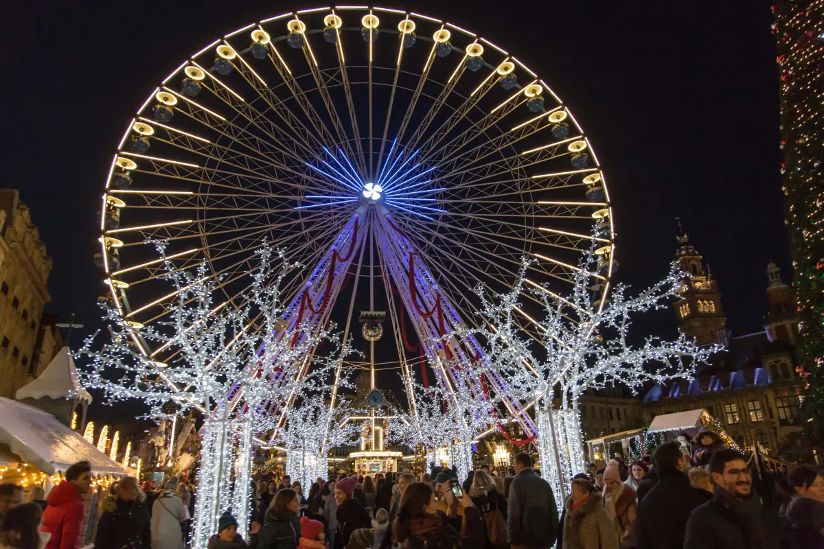 Das beleuchtete Riesenrad am Ende einer Allee aus Lichterbäumen, auf der dicht gefüllten Grand'Place