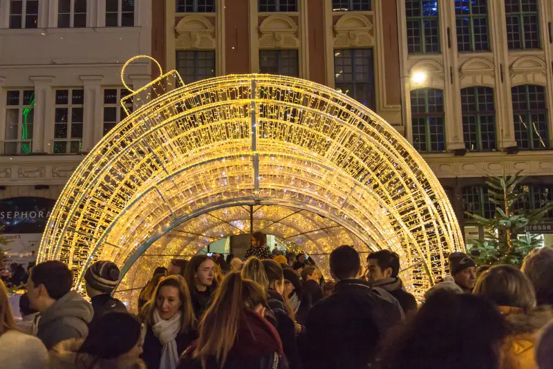 Eine riesige leuchtende Christbaumkugel, durch die die Besucher gehen, vor den Fassaden der Grand'Place