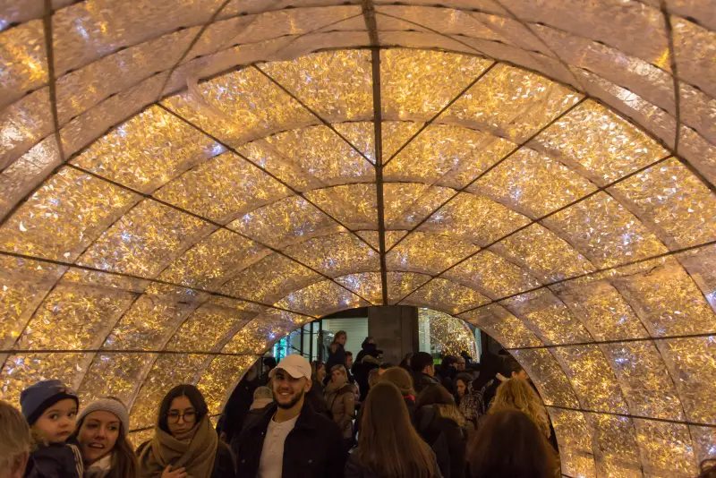 Im Inneren der Leuchtkugel: ein Tunnel aus goldenem Licht, durch den Spaziergänger gehen
