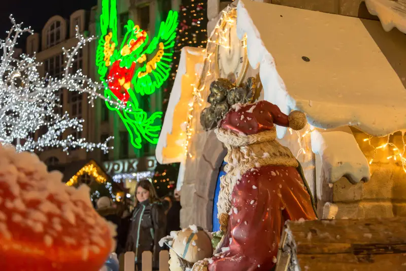Ein verschneites Holzhäuschen und ein Weihnachtsmann vor den beleuchteten Fassaden der Grand'Place
