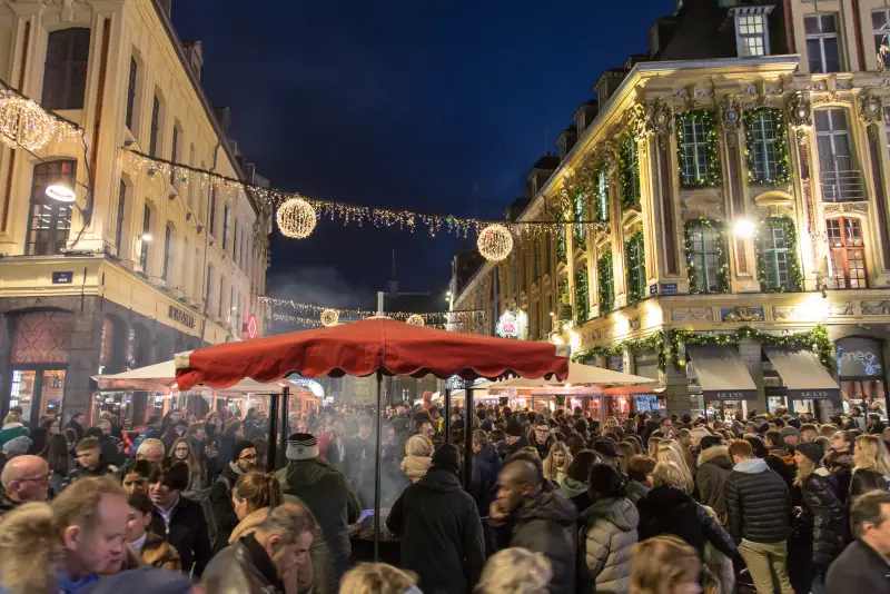 Eine Straße neben der Grand'Place unter Girlanden und Leuchtkugeln, voller Menschen