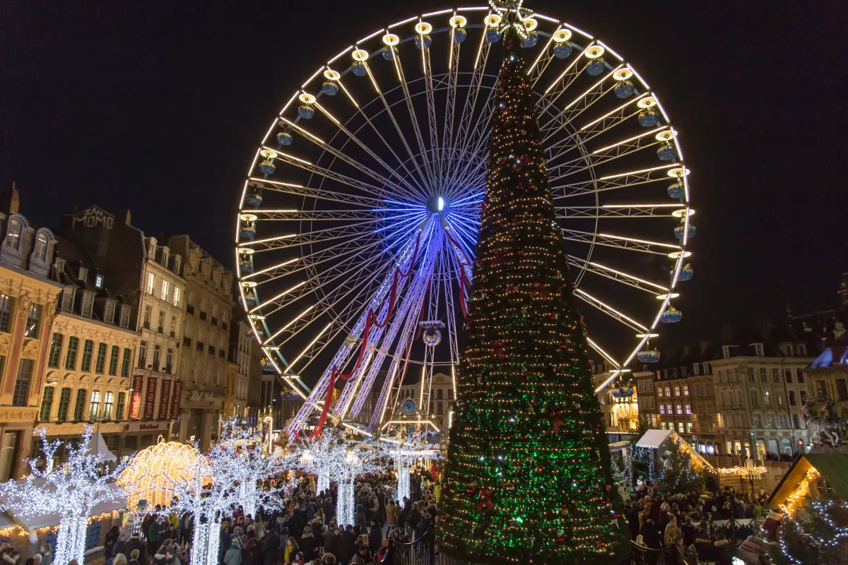 Das beleuchtete Riesenrad und der große Weihnachtsbaum auf der Grand'Place von Lille, Besucher zwischen Lichterbäumen