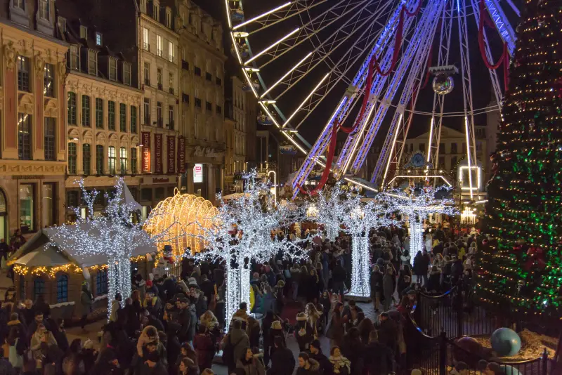 Die Grand'Place an einem Samstagabend: Besucher, Holzhäuschen, Lichterbäume, Riesenrad und großer Weihnachtsbaum