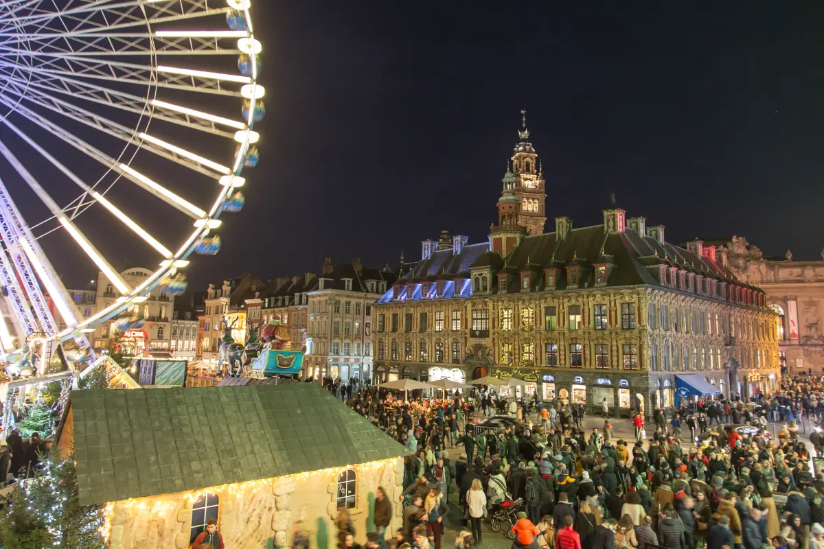 Die Grand'Place zur Weihnachtszeit: Riesenrad, ein Holzhäuschen, Besucher, die Alte Börse und der Belfried der Handelskammer