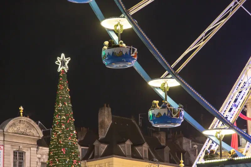 Gondeln des Riesenrads über den Dächern und der große Weihnachtsbaum mit einem Stern an der Spitze