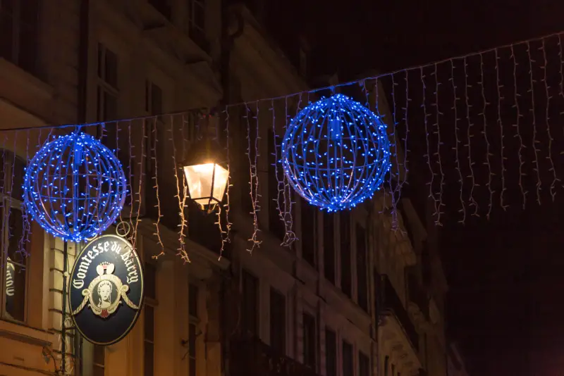 Blaue Leuchtkugeln und ein schmiedeeisernes Ladenschild in einer Straße der Altstadt